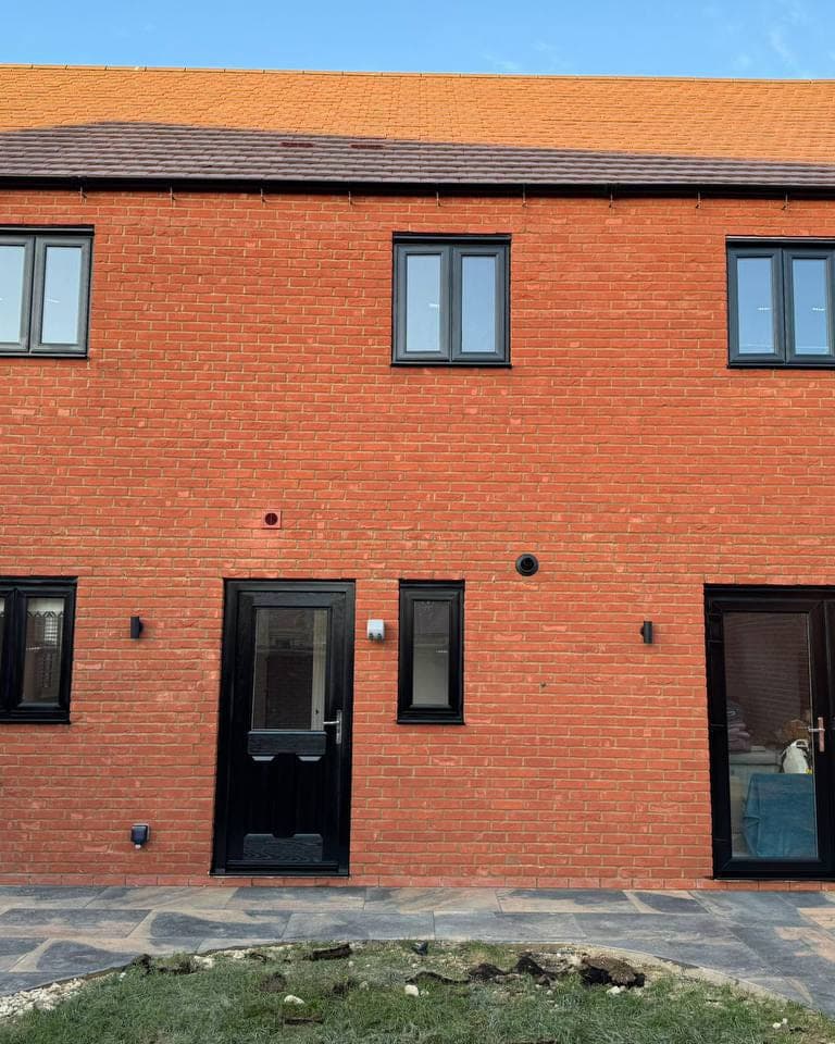 Black sprayed windows, French doors and a front door across a new build elevation